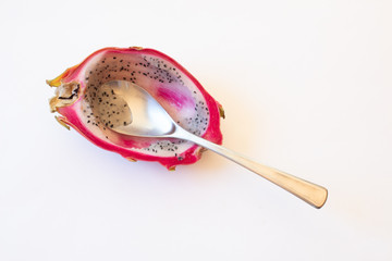 Close view of half of a dragon fruit with spoon, isolated on white, horizontal aspect