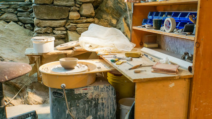 potter's studio or workshop with wheel, tools, clay, bowl in progress