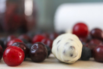 White chocolate candy and berries on a blurred background
