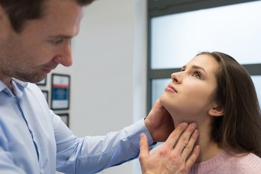 Physiotherapist giving neck massage to woman in clinic