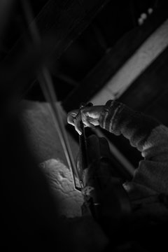 Man playing a violin in a shadowy room with focus to his fingers