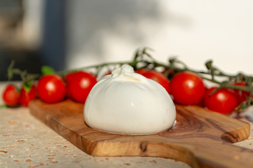 Fresh soft white burrata, buttery cheese, made from a mix of mozzarella and cream, original from Apulia region, Italy with tomatoes