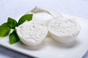 Fototapeta na wymiar Fresh soft white burrata, ball buttery cheese, made from a mix of mozzarella and ricotta cream, original from Apulia region, Italy, very popular soft cheese in USA