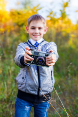 teenager in a black and white jacket in the fall with an old camera
