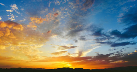 Beautiful sunset with the sun of orange tones behind the mountains and deep blue sky