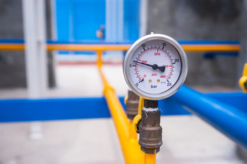 Closeup of manometer for measuring gas pressure. Pipes and valves at industrial plant.