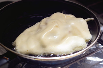 Chile nogada capeado y friéndose en una sarten 