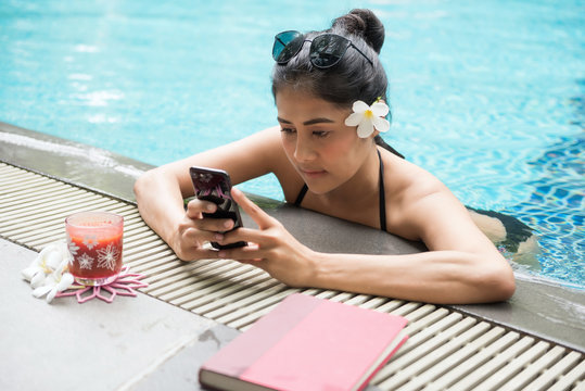 Sexy woman play smartphone at pool