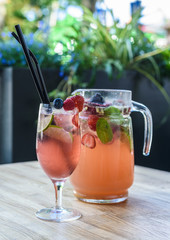 Fruity cocktail drink decorated with frozen or fresh raspberry, strawberry, mint, ice and soda.