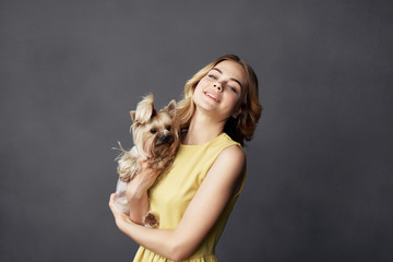 woman with a dog in her arms on gray background