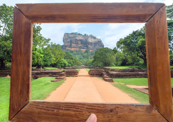 Wooden photoframe for composition with landscape of Sigiriya mountain and famous historical and archaeological site. Road through the forest around UNESCO world heritage site