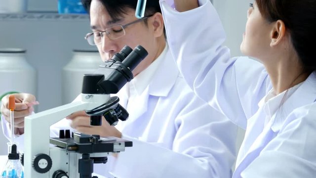 Asian Scientist looking to liquid in test tube. Science work at laboratory. People with medical, science, doctor, healthcare concept. 4K Resolution.