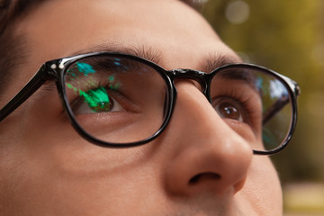 Close-up of man wearing glasses. Brown-eyed guy looking up. Healthy sight concept. Businessman, student in eyewear