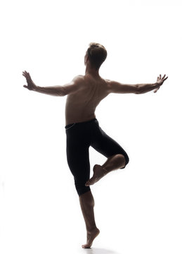 rear view, one young man back, ballet dancer, posing arms outstretched, standing on one leg in air, white background, photo shoot.