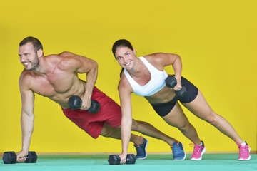 Beautiful fitness young sporty couple doing push ups together indoors.