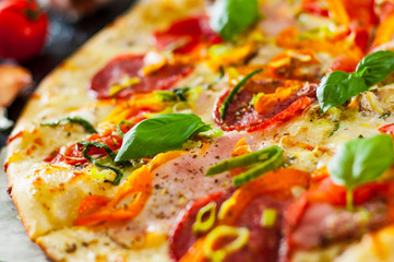 Pizza with Mozzarella cheese, Ham, Tomatoes, salami, pepper, pepperoni Spices and Fresh Basil. Italian pizza.  Close up.