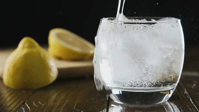 Soda water with ice cubes and lemon in the drink glass.