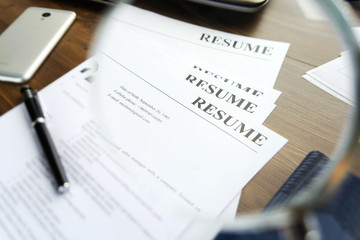 Resume (curriculum vitae, cv) and pen on a written wooden table. 