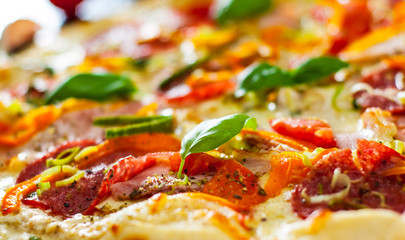 Pizza with Mozzarella cheese, Ham, Tomatoes, salami, pepper, pepperoni Spices and Fresh Basil. Italian pizza.  Close up.