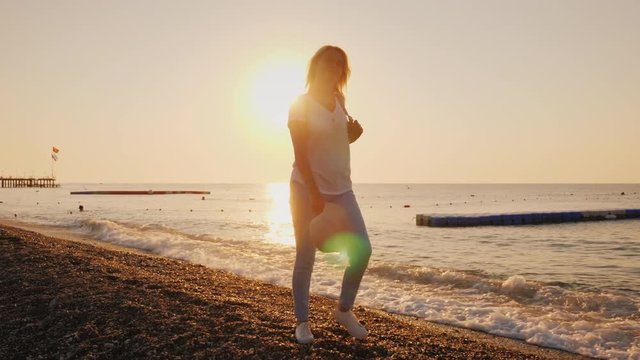 A happy woman walks carefree along the surf line, the sun rises over the sea. Holiday and vacation concept, escape from problems and fuss