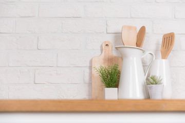 Fototapeta na wymiar Kitchen utensils and dishware on wooden shelf. Kitchen interior background