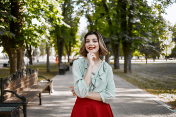 Fototapeta premium a woman in a red skirt walks in the park