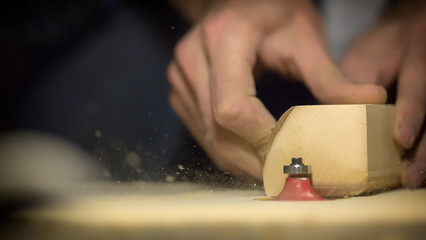 A large plan, hands of an artisan working on a wooden part