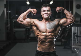 Fototapeta na wymiar Handsome strong bodybuilder athletic men pumping up muscles with dumbbells