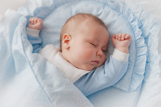 Baby's restful sleep. Newborn baby in a wooden crib. The baby sleeps in the bedside cradle. Safe living together in a bedside cot. The little boy dozed off under a knitted blanket.