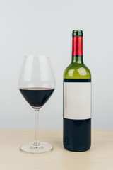 a glass and a bottle of red wine on the wooden table