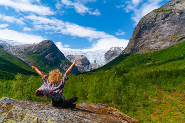 Woman cheering in front of the Bergsetbreen, a glacier in Norway