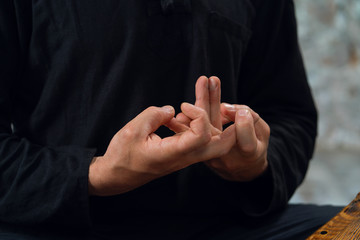 a man in black interlaced his fingers in mudra