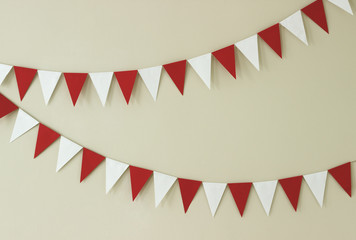 Obraz premium Triangular paper handmade garlands of white and red on a light wall.