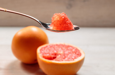 Grapefruit with spoon on a wood table. Close-up.