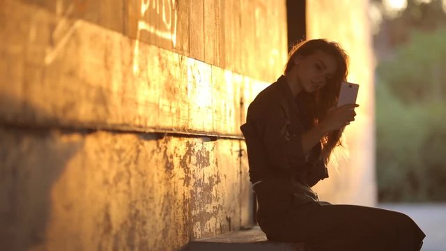 Video portrait of an attractive Caucasian white girl with beautiful hair. Happy girl in the underpass makes selfi on the smartphone.