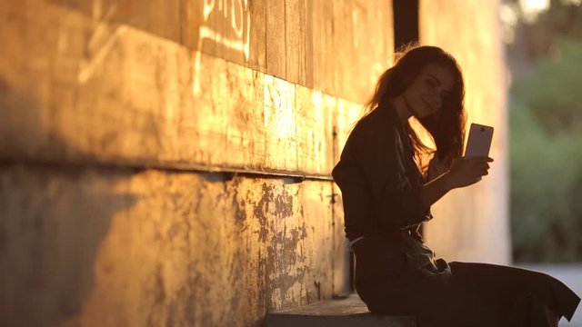 Video portrait of an attractive Caucasian white girl with beautiful hair. Happy girl in the underpass makes selfi on the smartphone.