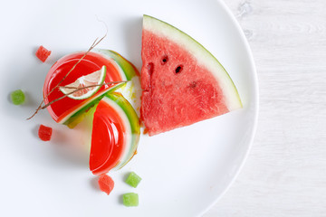 Watermelon dessert. Panakota and jelly in a white plate on the table background. Top view