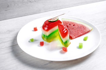 Watermelon dessert. Panakota and jelly in a white plate on the table background. Top view