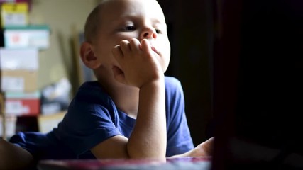The little boy looks away sideways.Watching TV.
