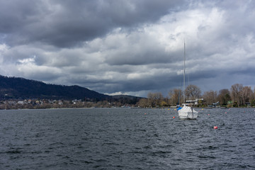 boat in harbour on lake zurich with clouds and blue water, zurich switzerland