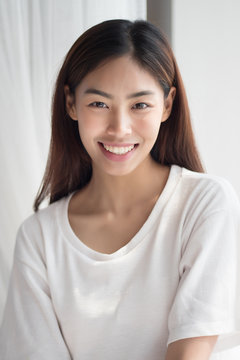happy smiling girl; portrait of positive relaxed happy smiling asian woman smiles in indoor home environment; young adult asian persian woman or asian middle east woman model