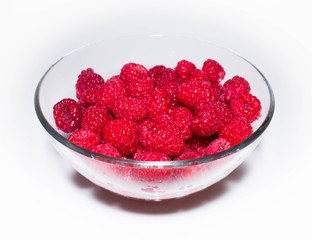 juicy red raspberry berry in a transparent glass plate
