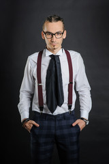 Young handsome boy in white shirt with tie and glases, hands in pockets