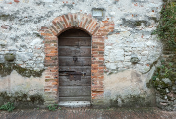 alte Holztür mit rostigen Beschlägen in einer Natursteinmauer