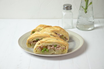 Salty braid with potatoes, ham and peas on white wooden table