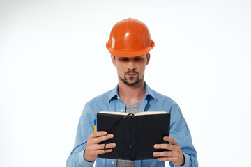 a builder in a helmet looks at a notebook