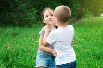 Children - a boy and a girl are playing in nature. The boy is hugging the girl. Children are having fun and laughing