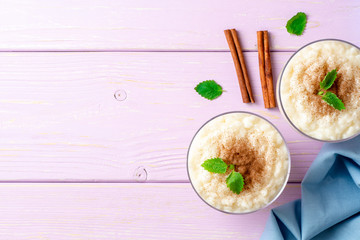 Rice pudding with cinnamon and mint on light purple wooden background