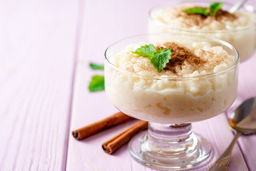 Rice pudding with cinnamon and mint on light purple wooden background