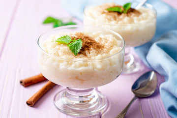 Rice pudding with cinnamon and mint on light purple wooden background